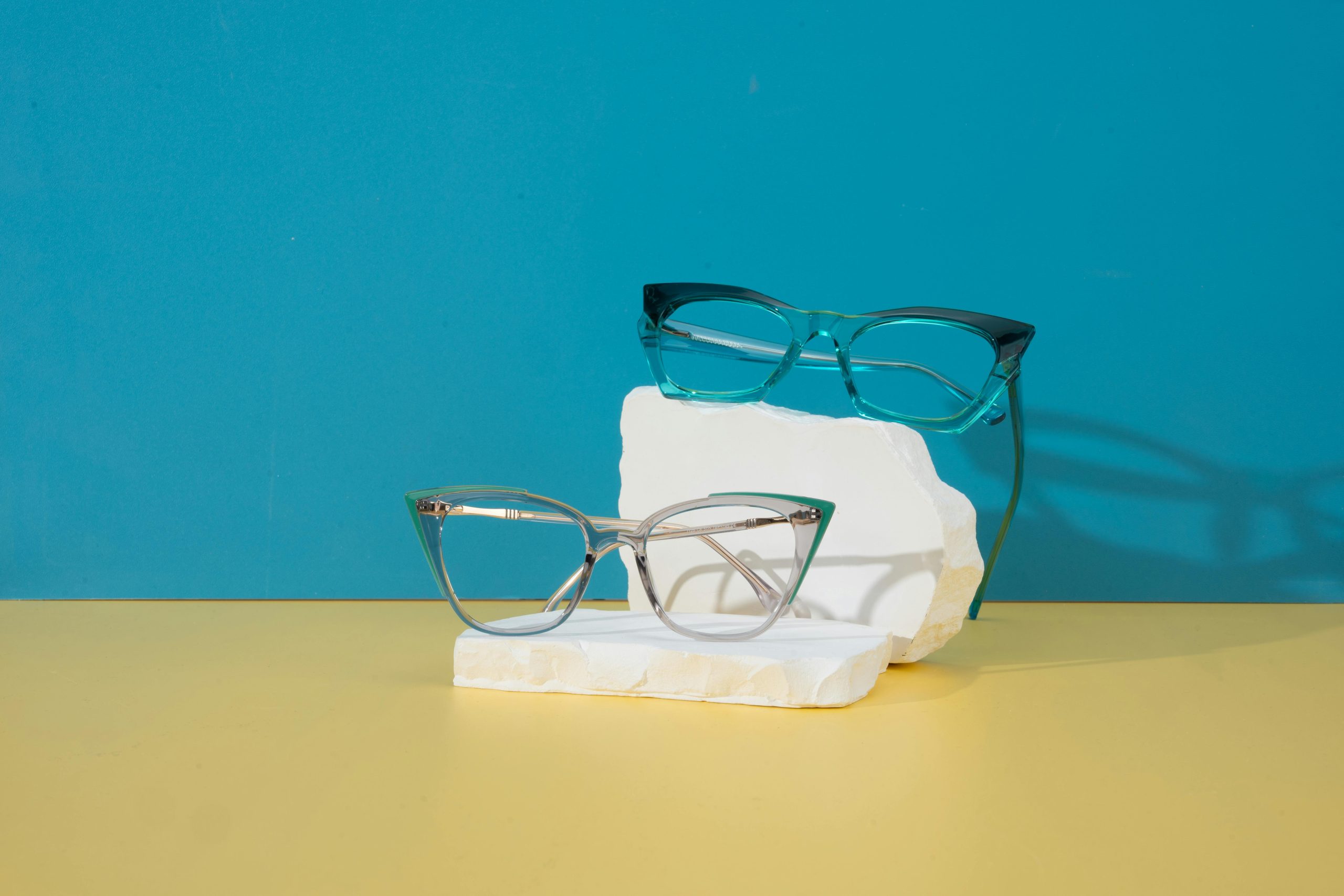 Stylish cat-eye glasses displayed on a vibrant blue and yellow background.